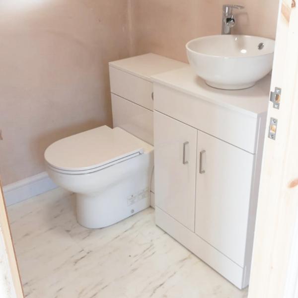Toliet and sink with plumbing hidden by under sink cabinet freshly plastered WC
